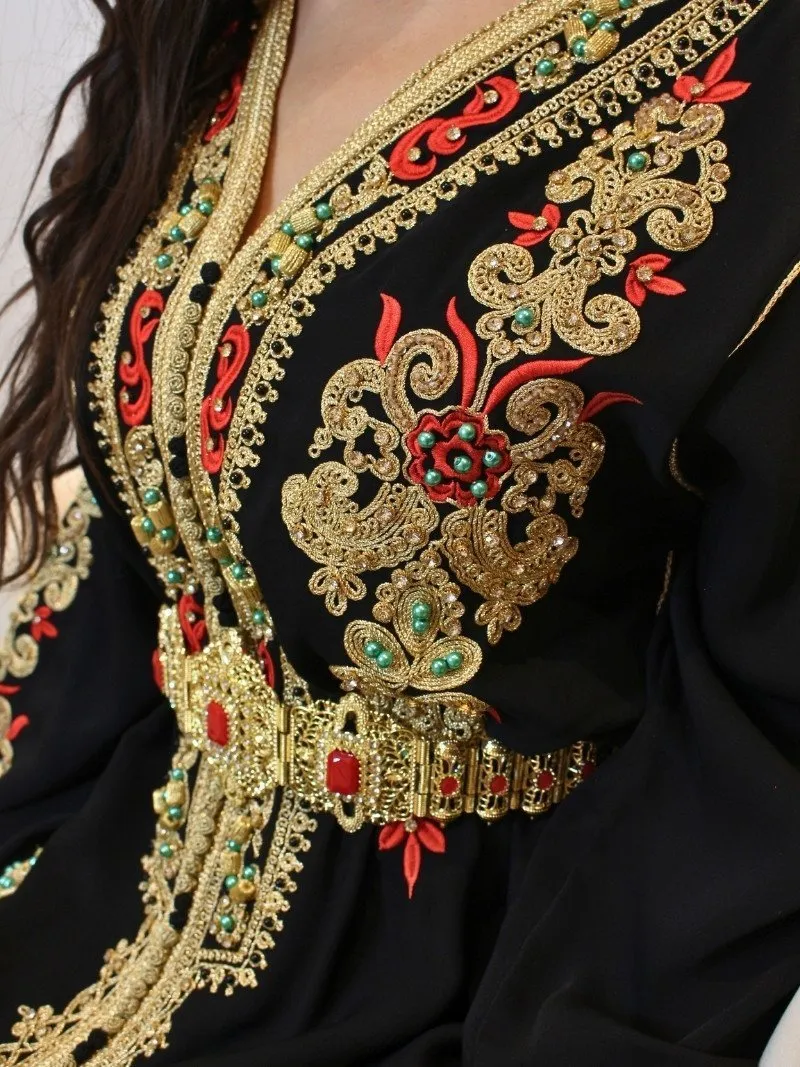 Caftan Mounia noir en crêpe avec broderie dorée et motifs rouges, disponible en tailles M, L et XL.