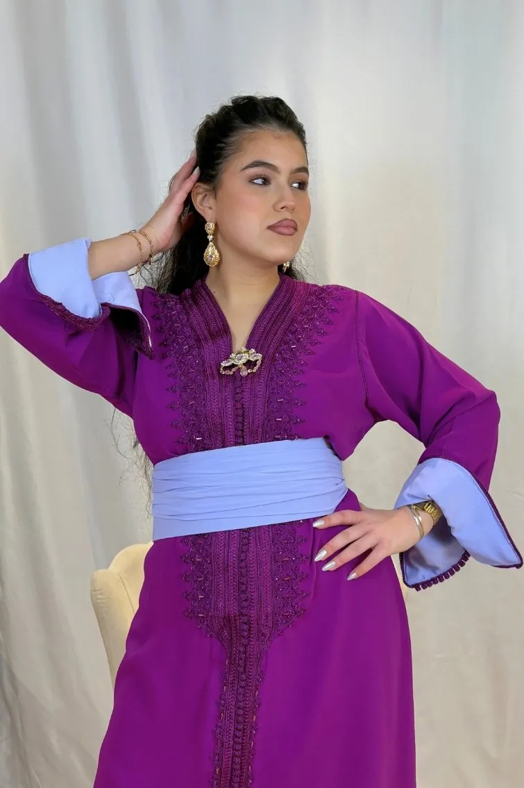 Femme portant un caftan violet orné de broderies ton sur ton, manches avec intérieur bleu clair et ceinture assortie.