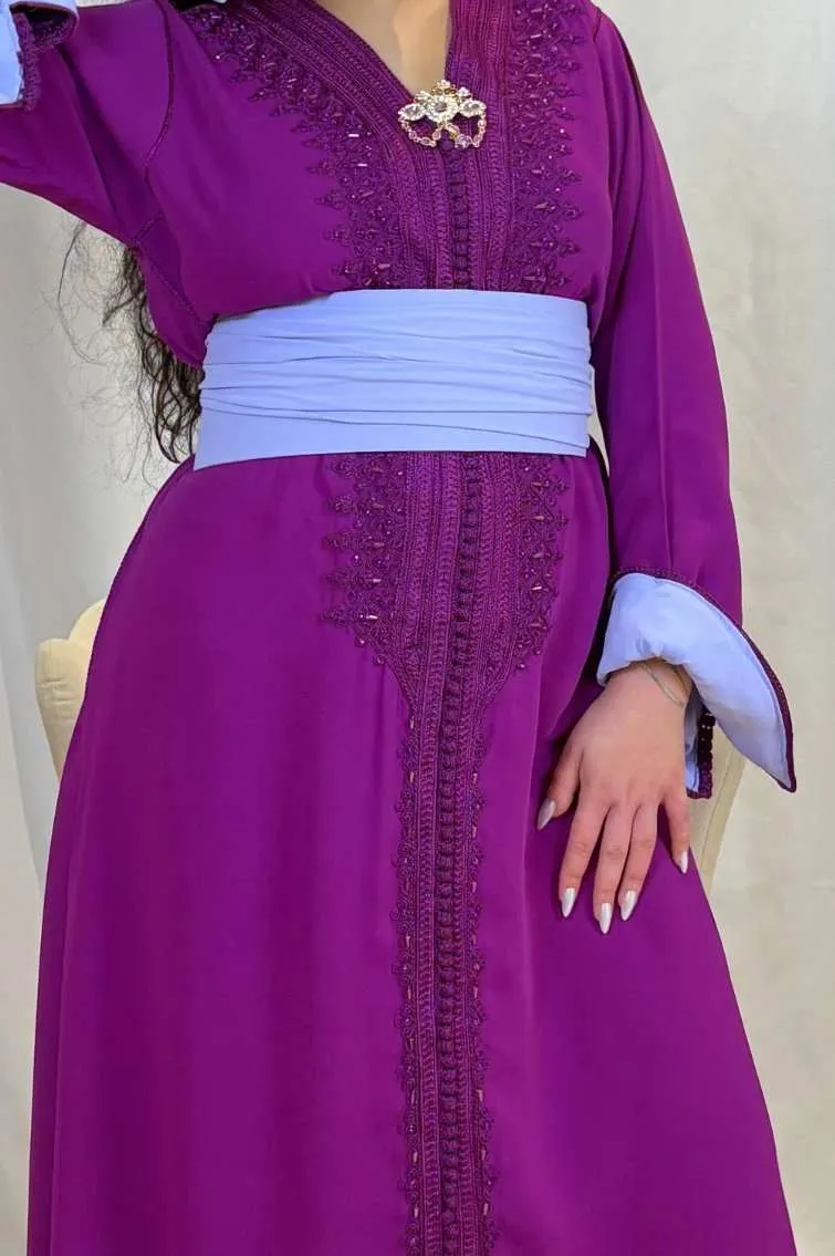 Femme portant un caftan violet orné de broderies ton sur ton, manches avec intérieur bleu clair et ceinture assortie.