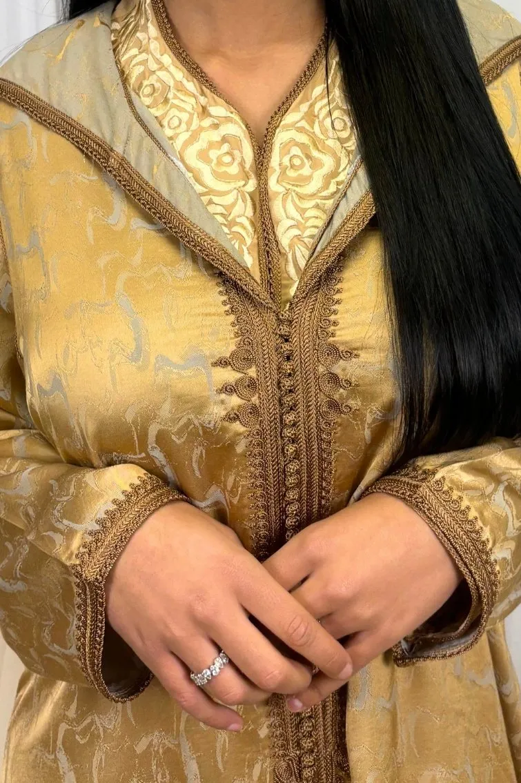 Une femme portant la jellaba Kamkha en 2 pièces, avec une gandoura intérieure en crêpe Bronze et une pièce extérieure en tissu Kamkha, exécutant une pose élégante.