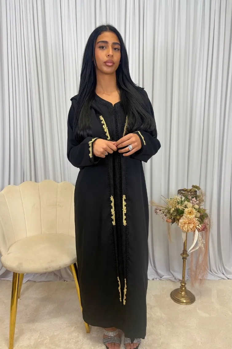 Une femme portant une jellaba 2 pièces en crêpe noir, avec une gandoura intérieure en crêpe et un selham extérieur, exécutant une pose élégante.