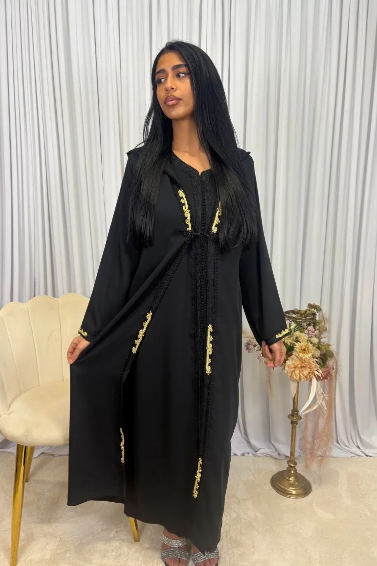 Une femme portant une jellaba 2 pièces en crêpe noir, avec une gandoura intérieure en crêpe et un selham extérieur, exécutant une pose élégante.